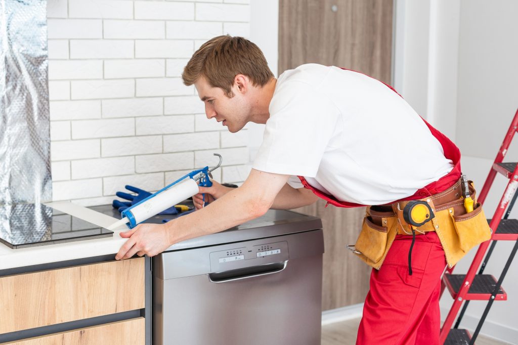 Gloved craftsman installs hob in kitchen. Household Appliance Installation Services Concept