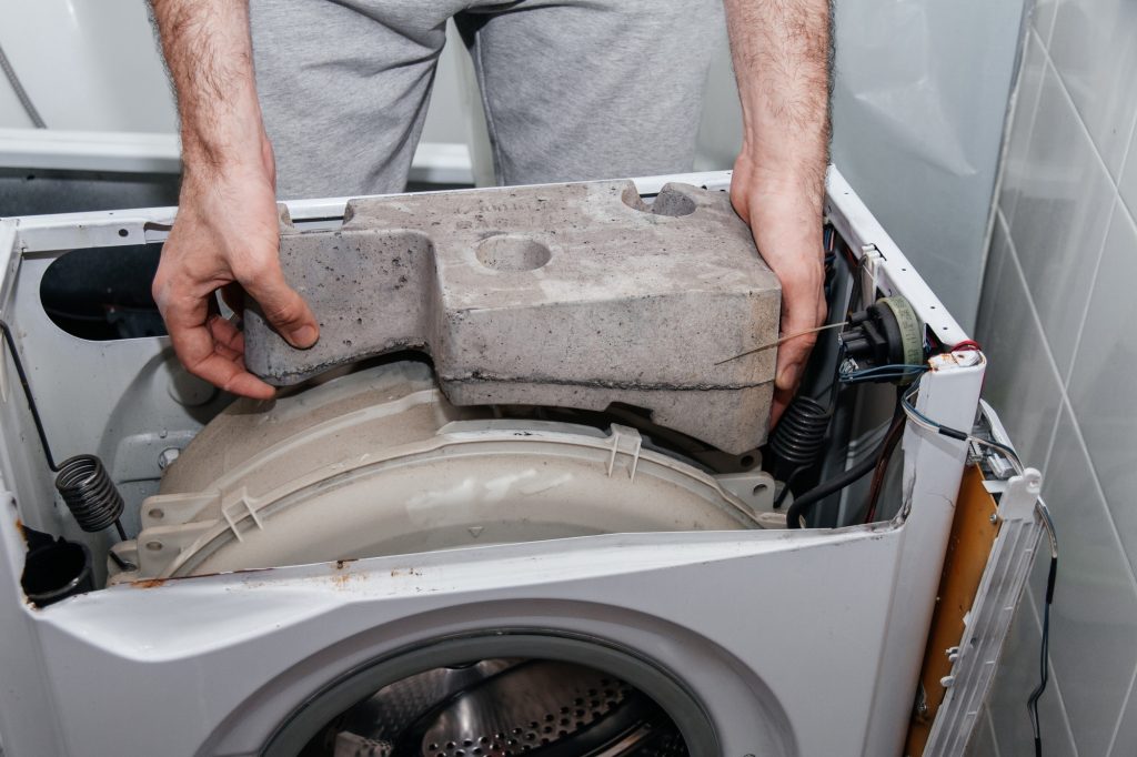 Handyman repairing a washing machine. The hands of a man repair a washing machine.
