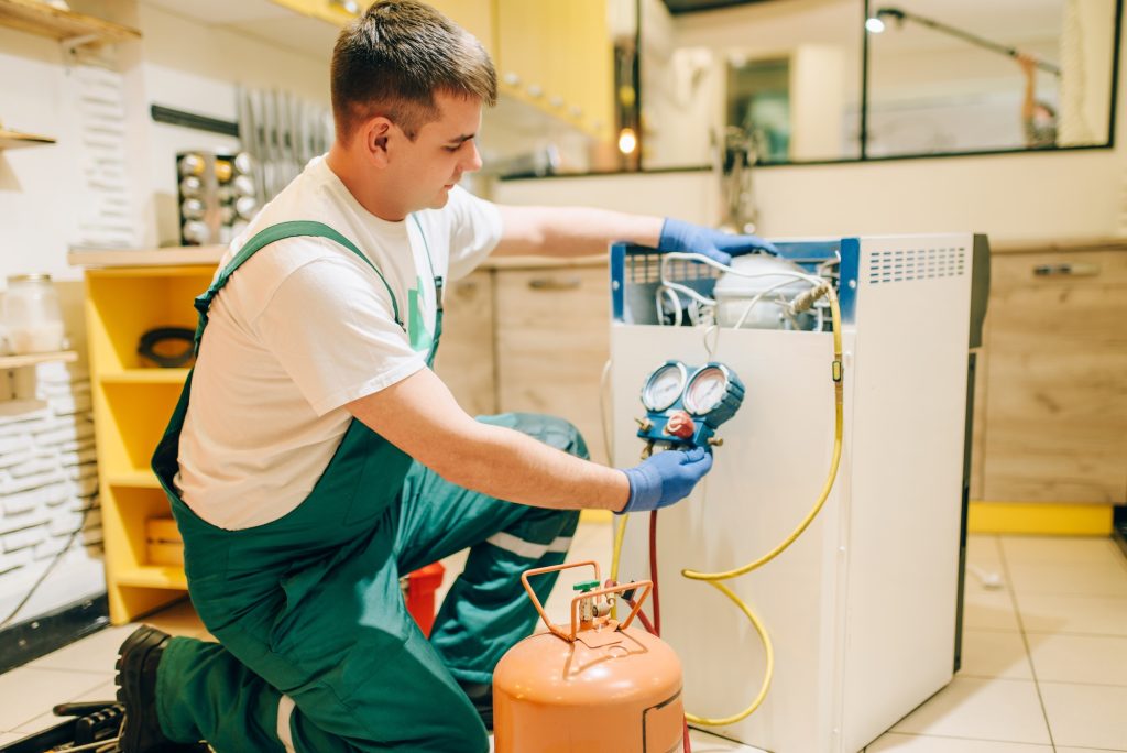 Worker in uniform fills compressor of refrigerator