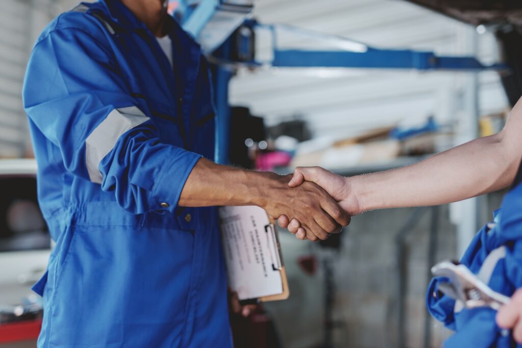 Auto mechanic handshake successful colleague in auto service center To congratulate the success
