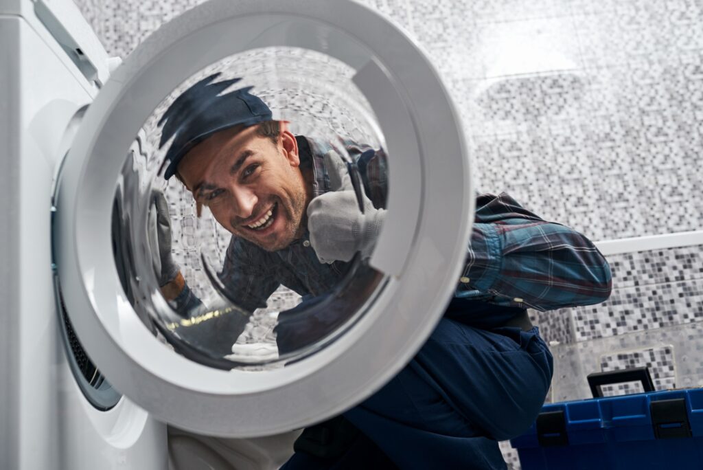 Glad of own results. Working man plumber in bathroom checking washing mashine