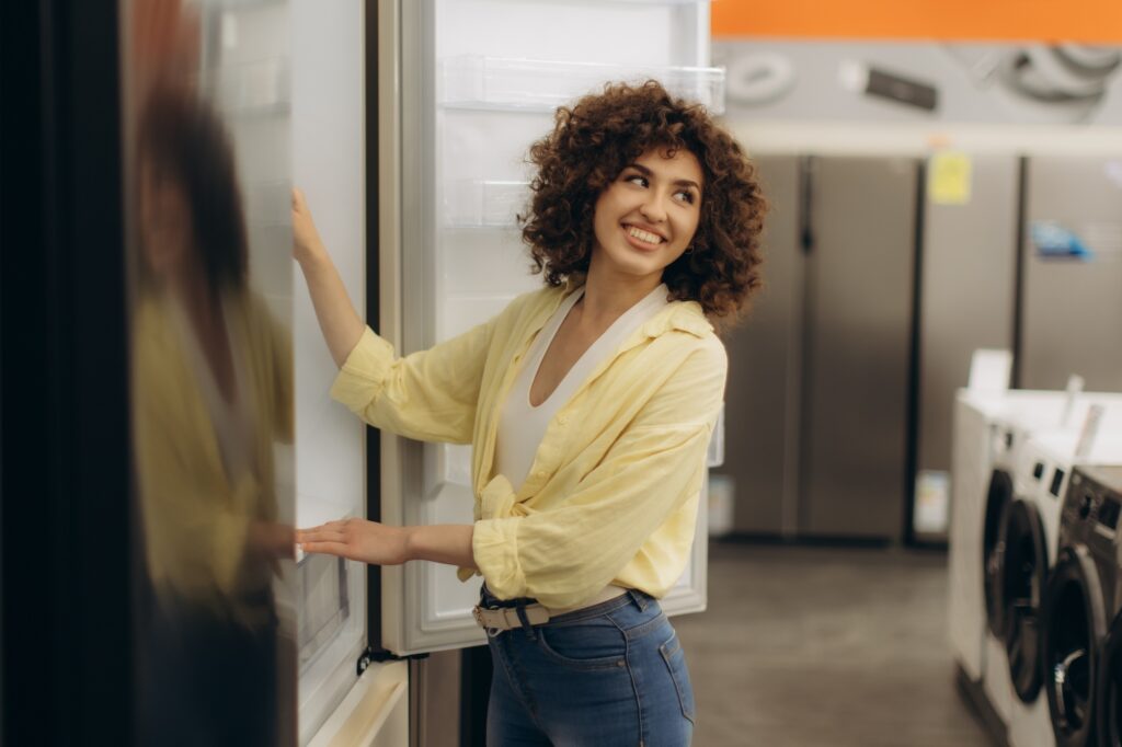 Smiling Woman Exploring Appliances in Modern Electronics Store
