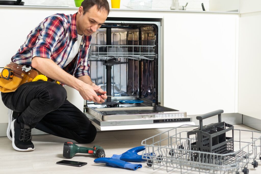 Worker repairing the dishwasher in the kitchen