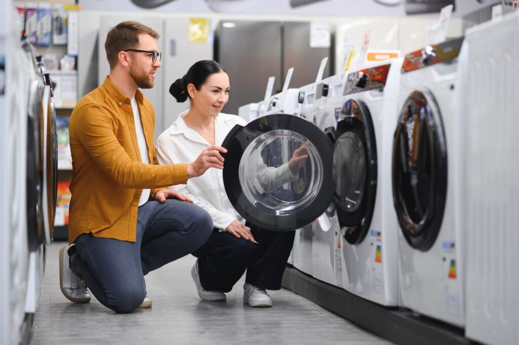 Young couple choosing washing machine in hypermarket.