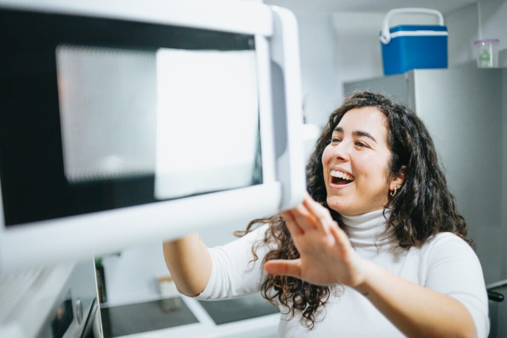 Young plus size spanish woman cooking on a microwave at a modern kitchen