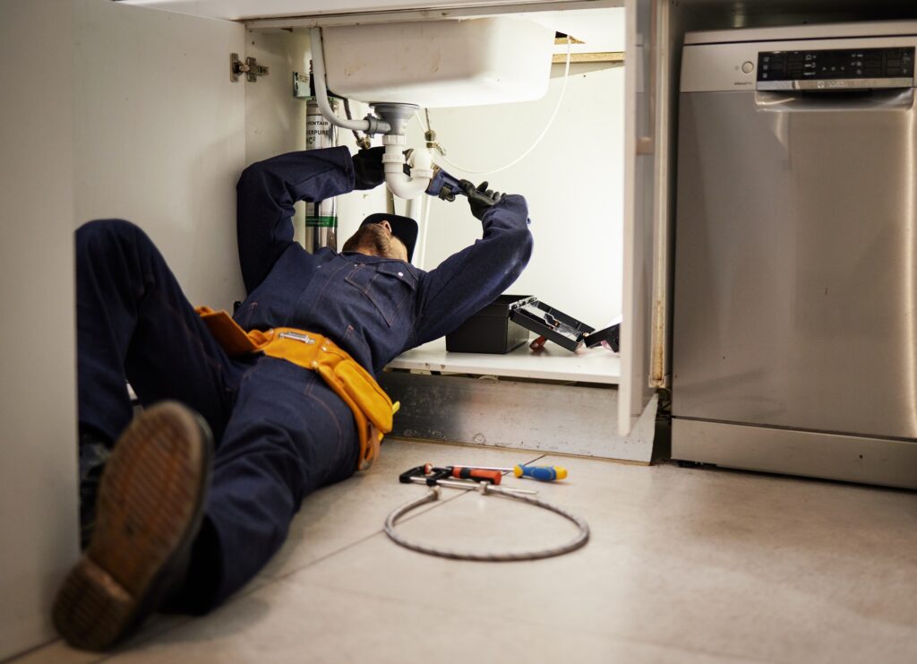 Kitchen, maintenance and renovation with a plumber on the floor of a home to fix a leak, issue or p