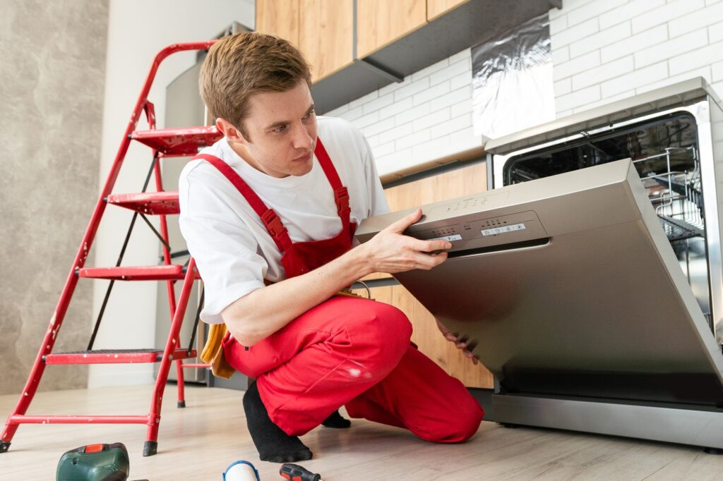 Repair of dishwashers. Repairman repairing dishwasher in kitchen