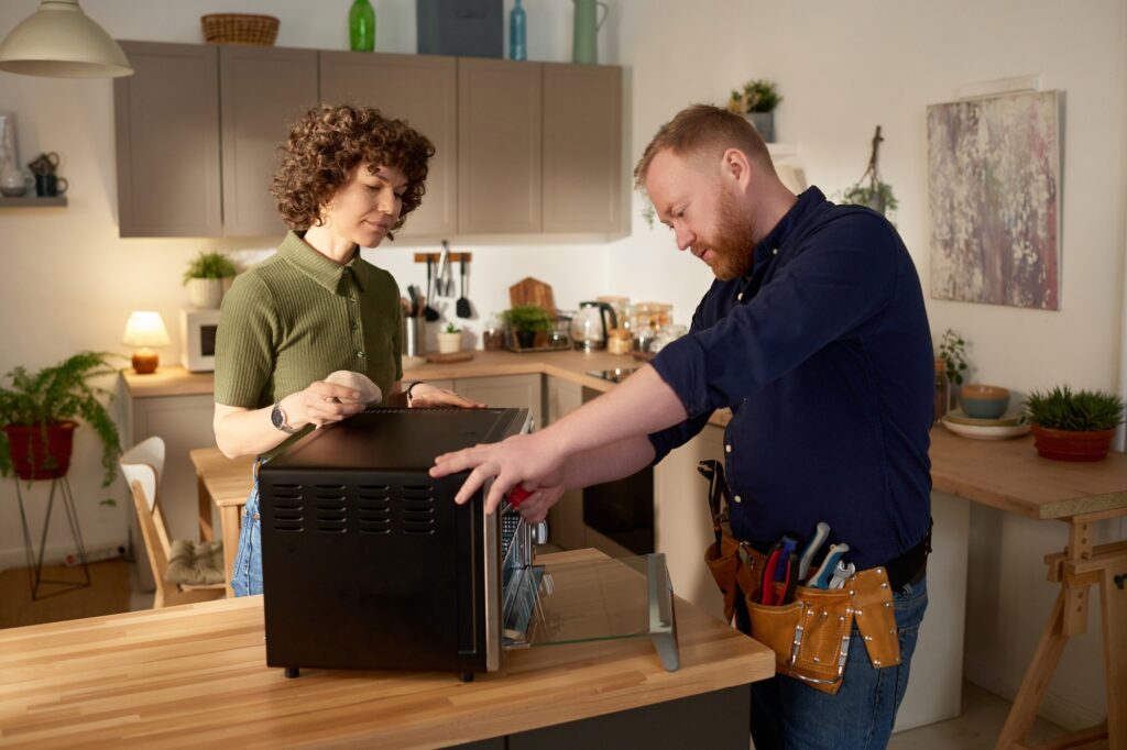 Repairman fixing microwave oven at home