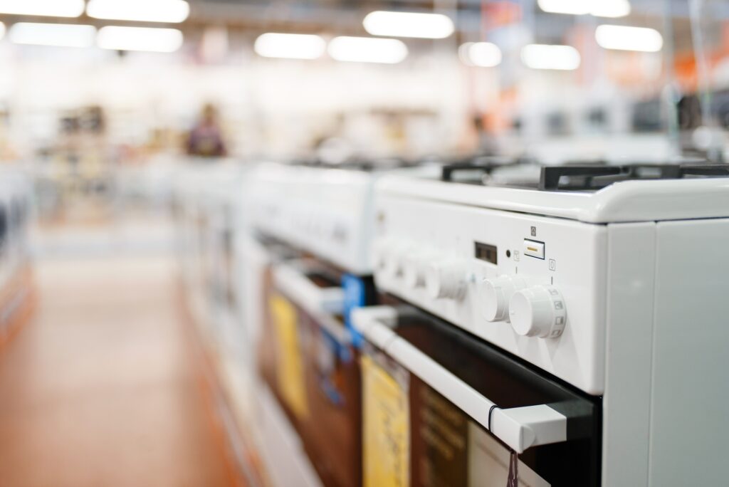 Row of new gas stoves in electronics store, nobody