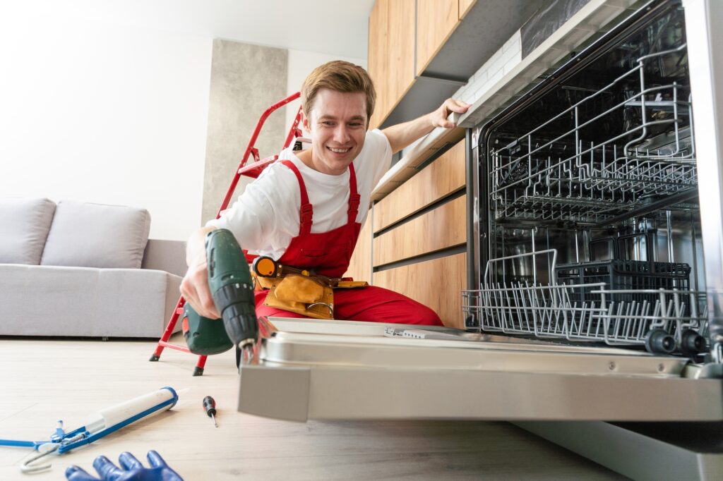 Concept maintenance service of home appliances. Worker cleans filter in the dishwasher. Male