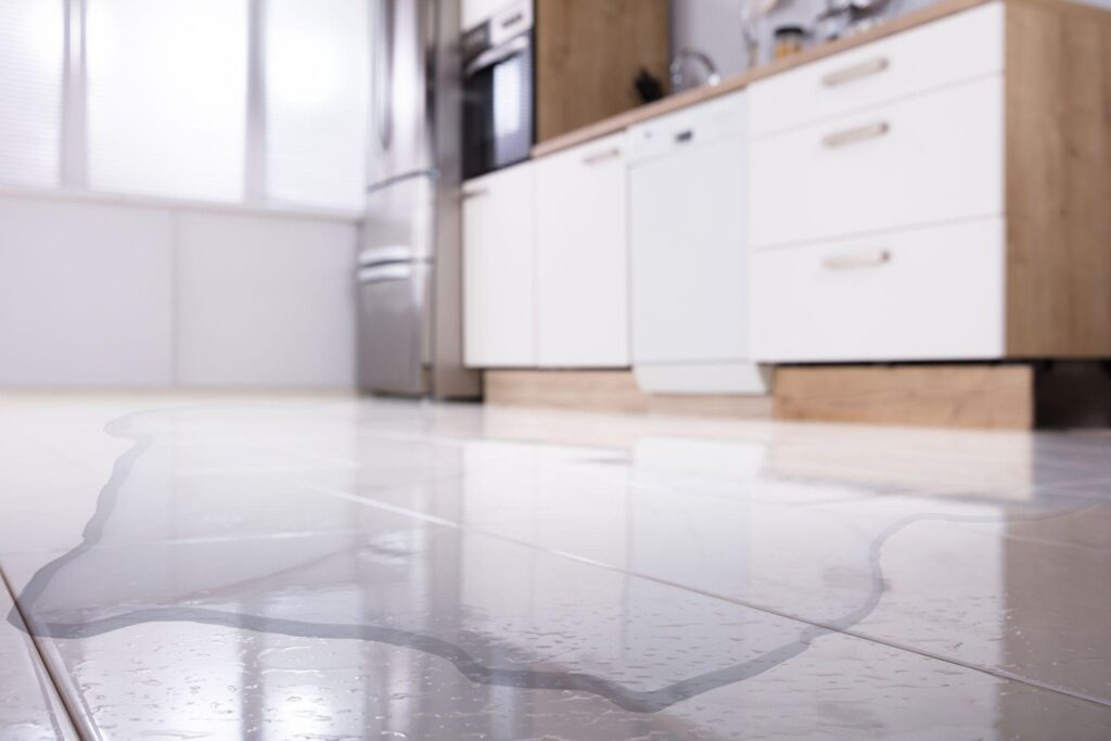 A kitchen floor covered with water reflecting light and creating a slippery hazard