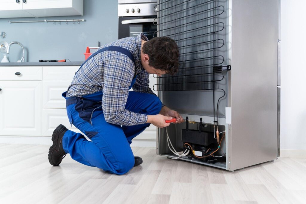 A man wearing overalls is fixing an appliance tools scattered around him in a tidy workshop environment