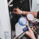 A technician holds a gauge near a gas furnace assessing its pressure for safety and efficiency